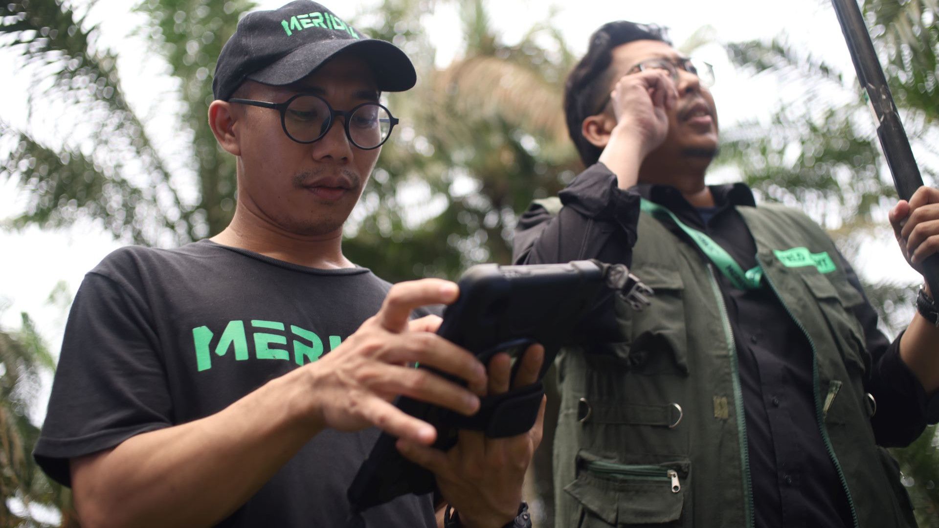 Two men in a forest wearing black and green clothes, investigating deforestation-free and traceability requirements.
