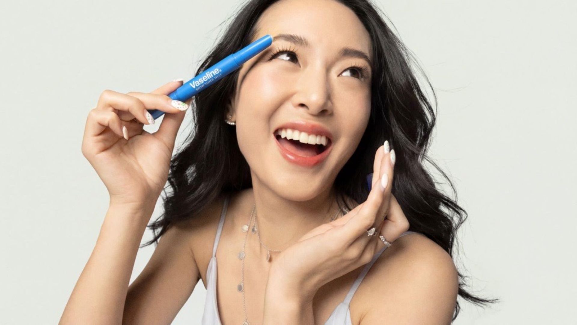 A photo of creator Jen Chae holding the Vaseline Originals Brow Tamer Jelly product she helped Vaseline design.