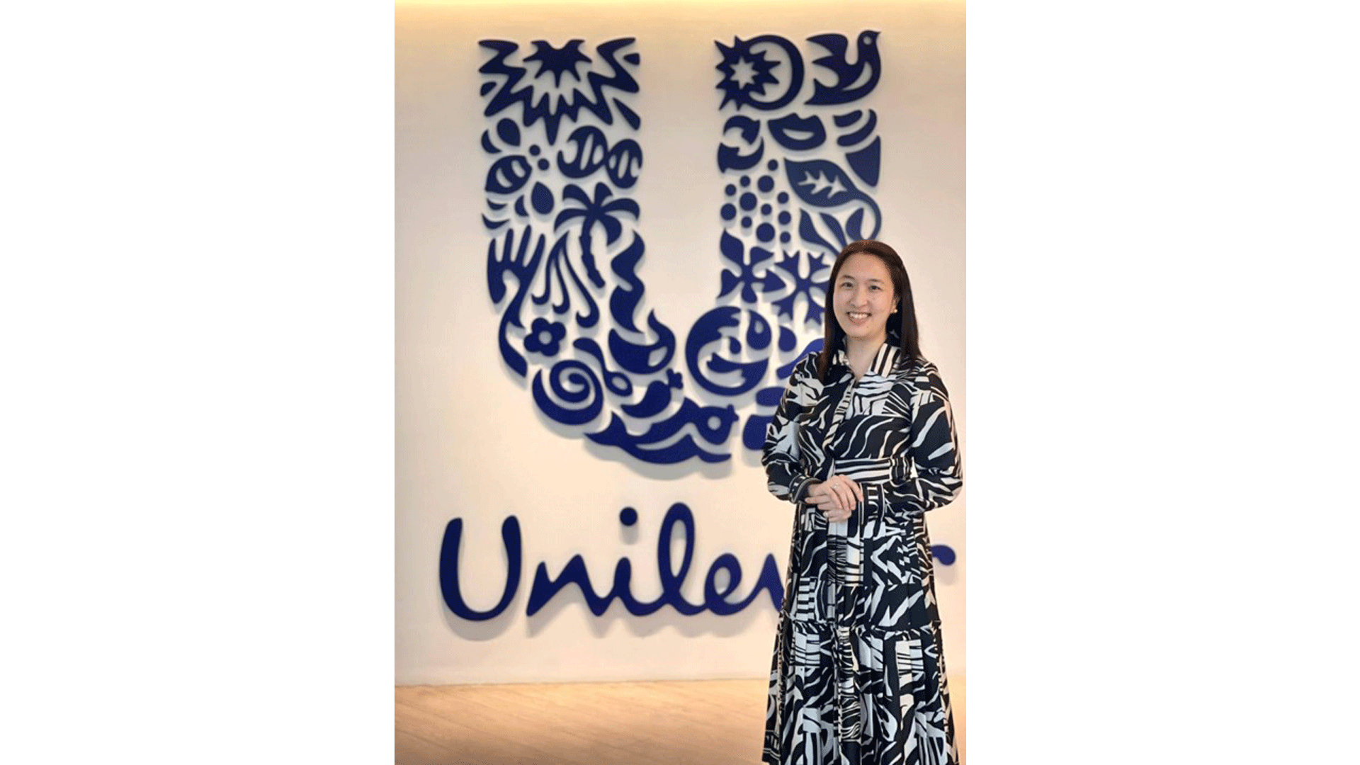 Kristine Go poses in front of a big Unilever logo mounted on a wall