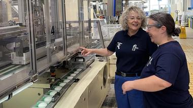 Two female workers standing next to a Dove Beauty Bar production line at Unilever’s Mannheim factory in Germany.