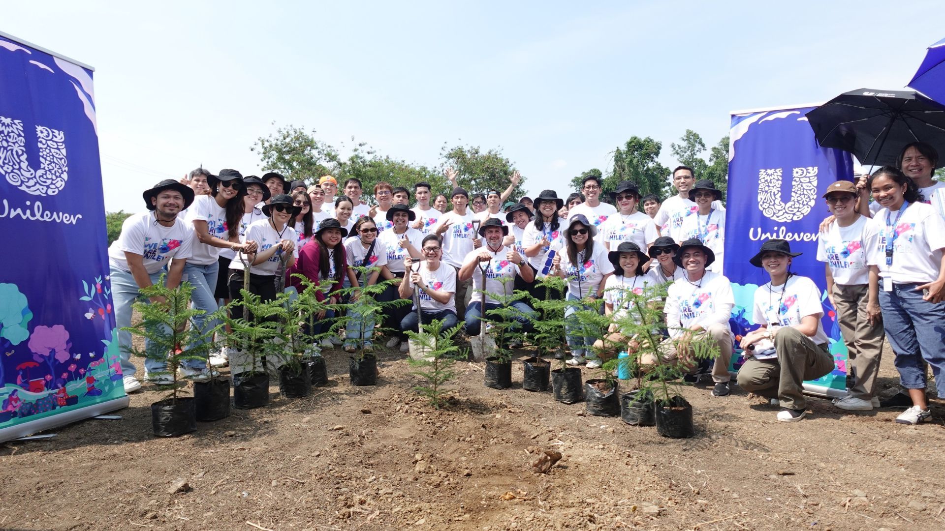  A group of Unilever Philippines employees pose outdoors together with trees to be planted on factory grounds