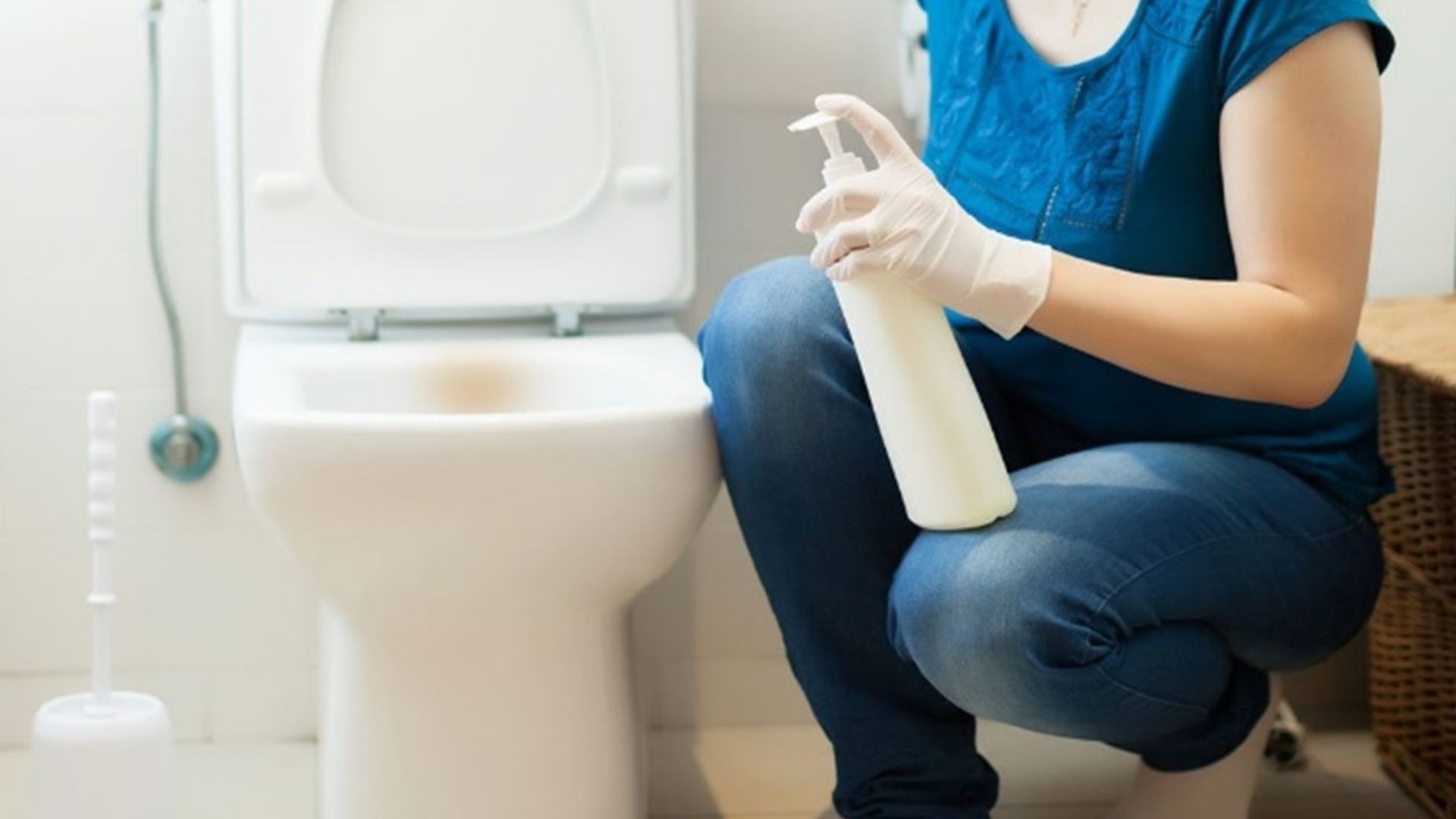 Woman putting a disinfectant on a high-touch area in the toilet