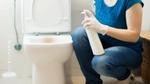 Woman putting a disinfectant on a high-touch area in the toilet