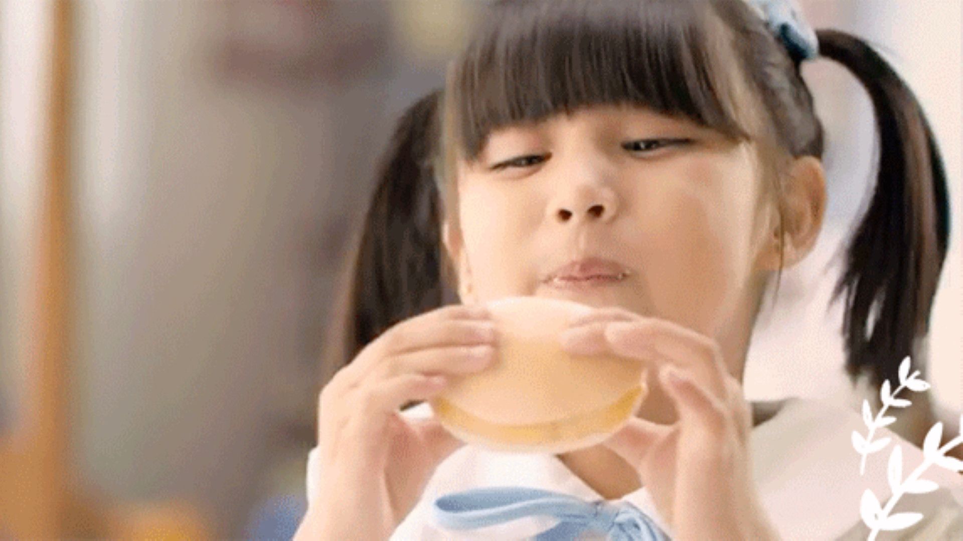 Young girl with pigtails happily eats a snack.