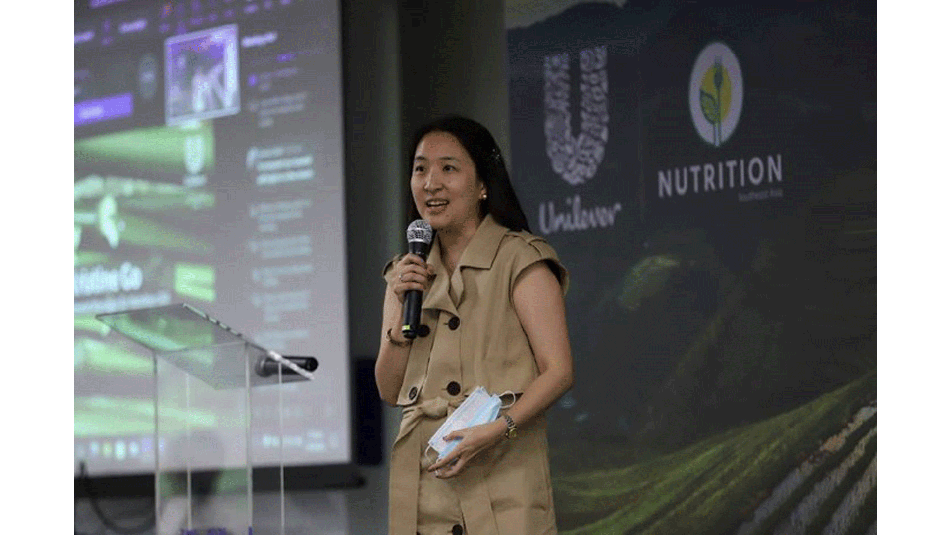 Kristine Go speaking with a micropone. Behind her are the Unilever and Nutrition Southeast Asia logos
