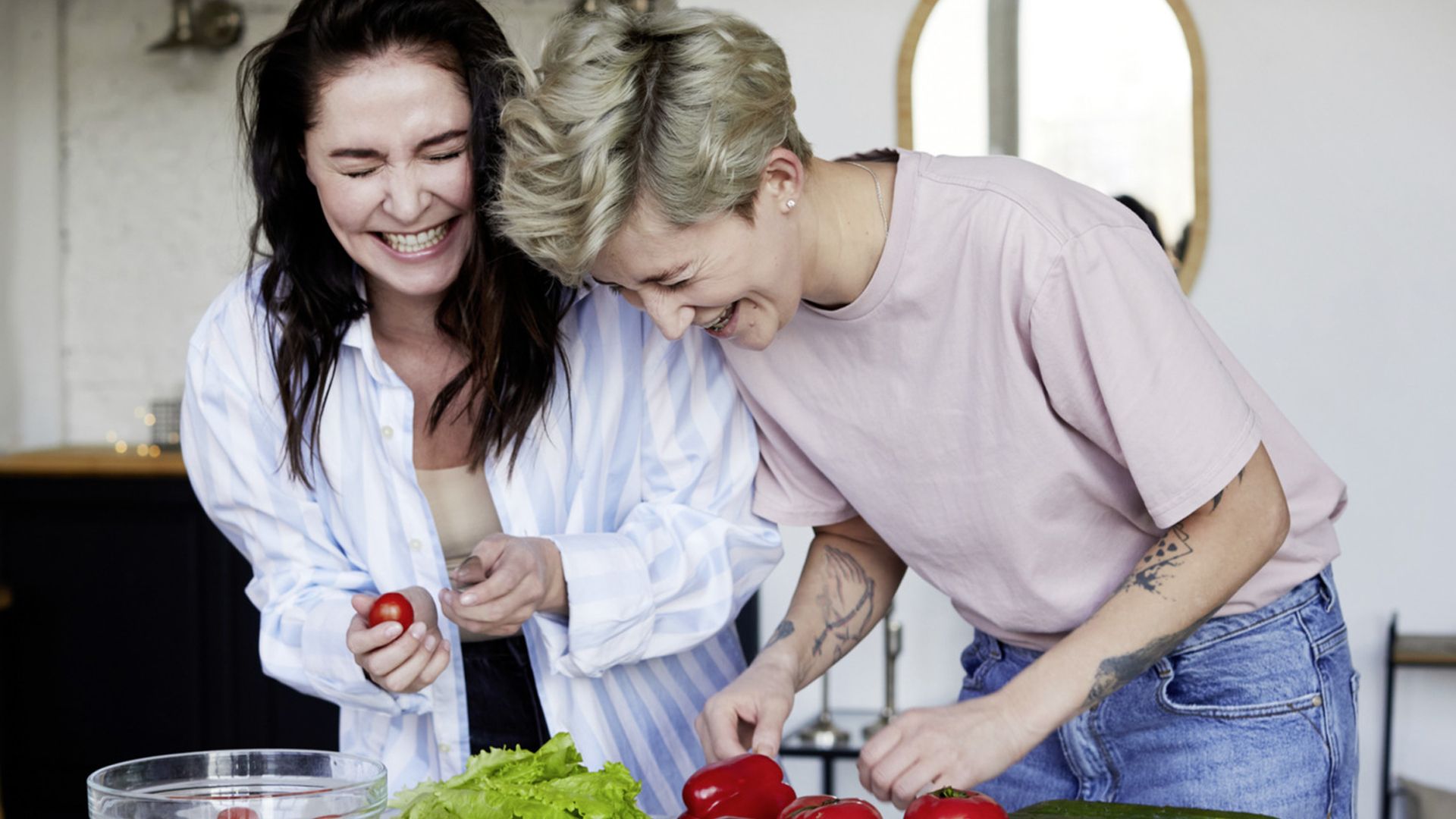 A man and a woman have their heads touching each other, with the man looking intently at the girl and the girl slightly closing her eyes while smiling