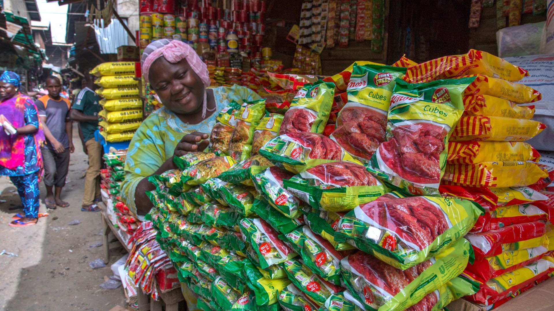 Small shop owner displaying bags of Knorr stock cubes on a stall