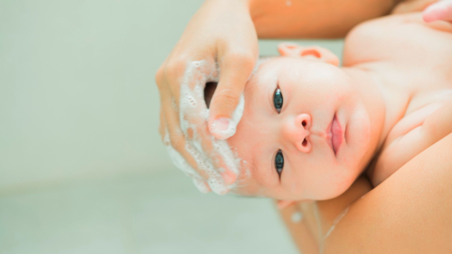 A mother shampooing her newborn’s hair.