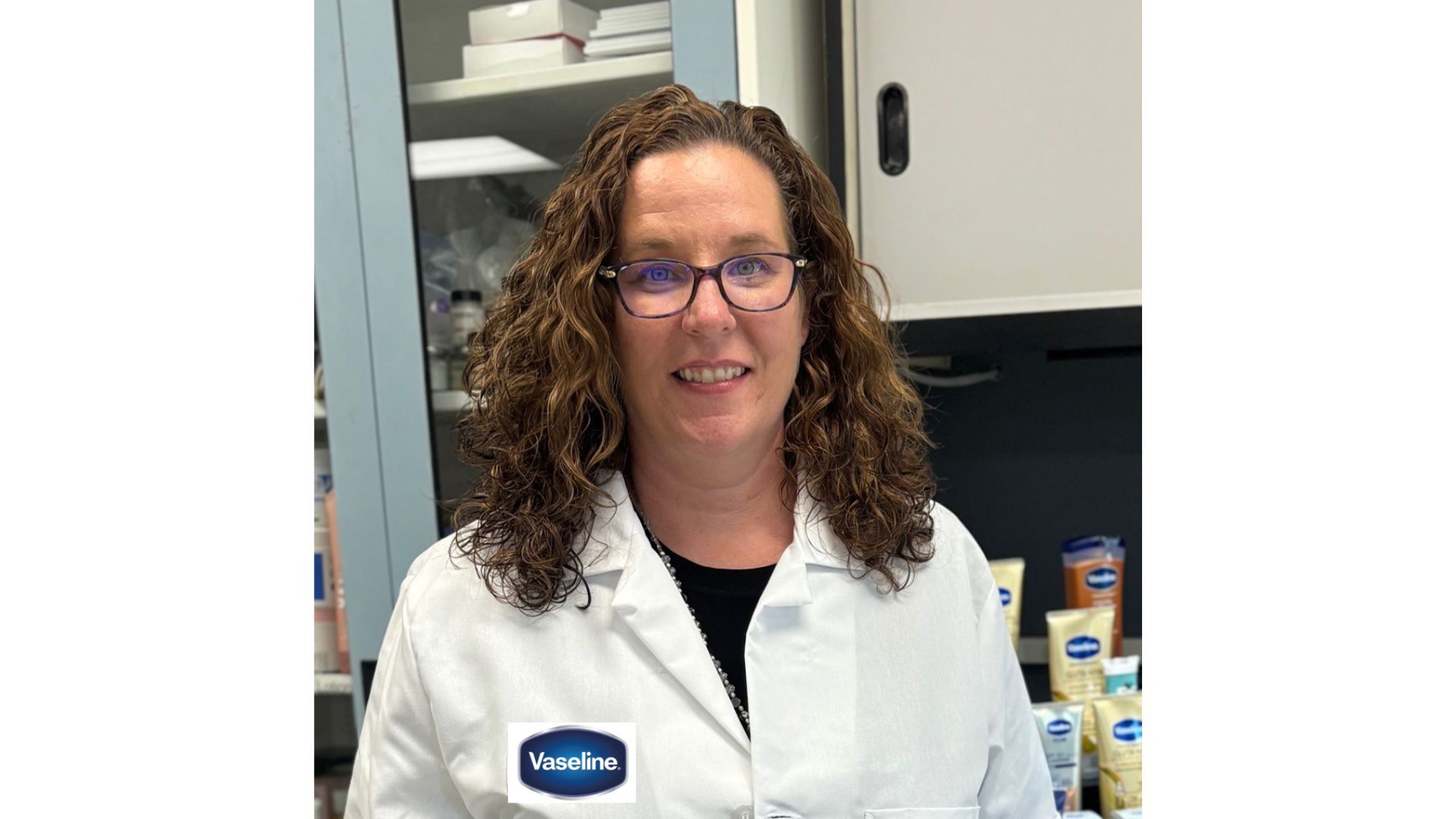 A photo of a scientist who worked on the Vaseline Verified campaign. A white woman with curly hair and glasses.