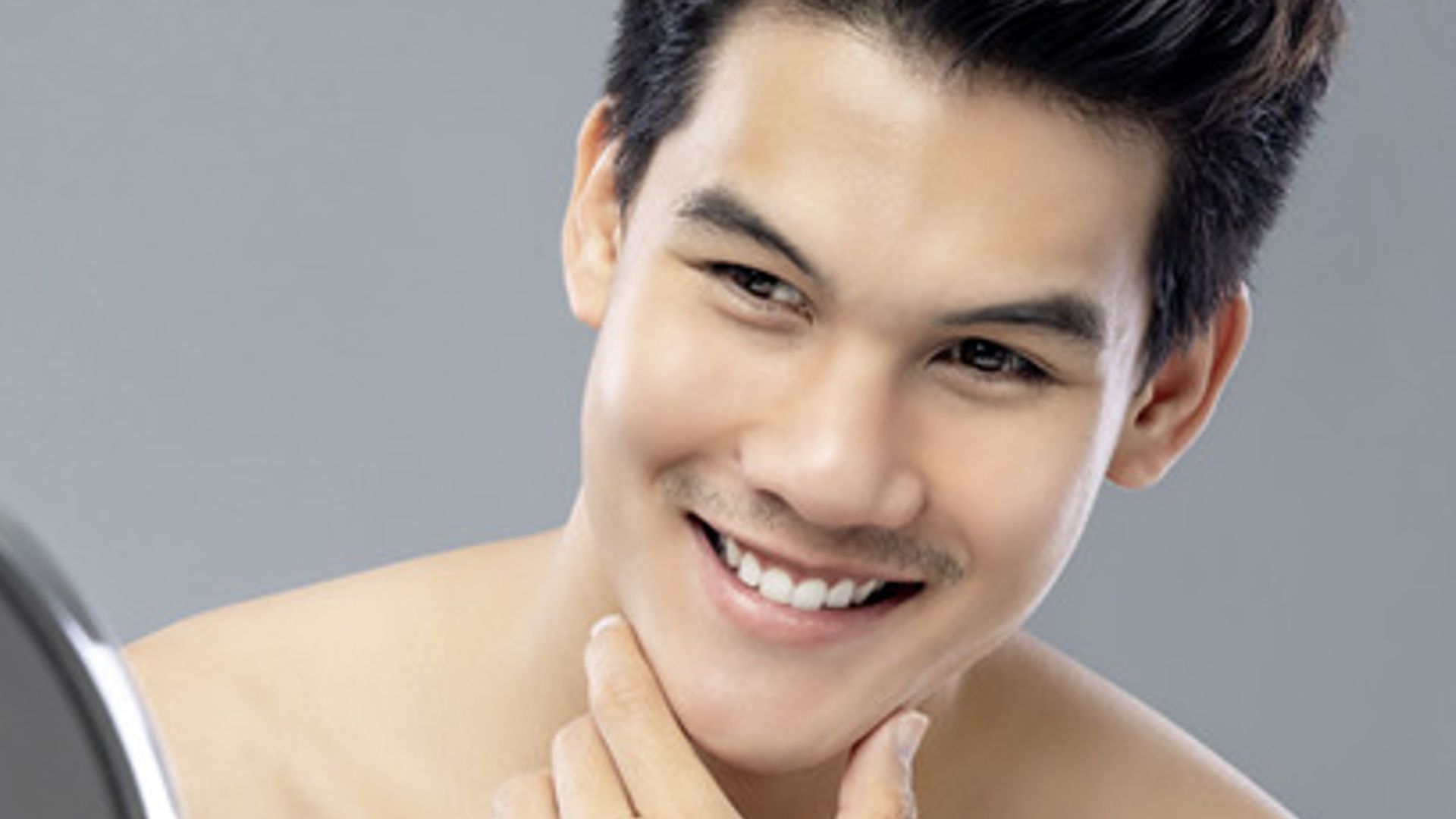 An Asian guy is looking at himself in the mirror, smiling after using Master Philippines